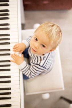 Tatlı olumlu yürümeye başlayan çocuk piyano. Küçük çocuklar, çocuk okulda müzik aletleri öğrenme için erken müzik eğitimi