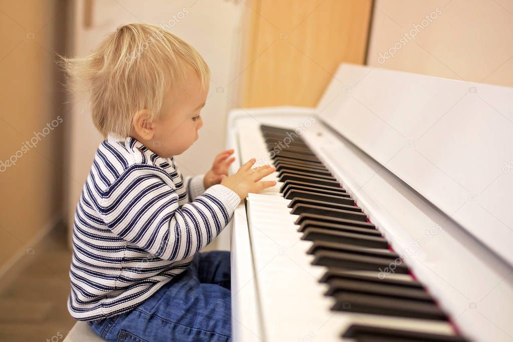 Sweet positive toddler child playing piano. Early music education for little kids, children at school, learning music instruments
