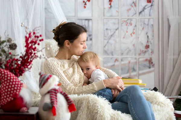 Mãe Amamentando Seu Filho Criança Sentada Poltrona Aconchegante Nevando Fora — Fotografia de Stock