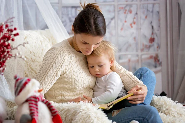 Anne, bebeğini emziriyor rahat koltukta oturuyor, kış vakti kar yağıyor.
