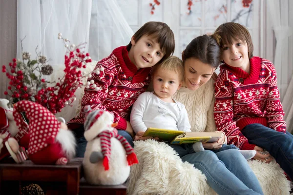 母は彼女の息子 雪に覆われた冬の日 冬の居心地の良いアームチェアに座っている子供に本を読む — ストック写真