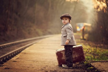 Çok güzel çocuk bavul ve oyuncak ayı, vintage bir görünüm taşıyan tren bekleyen bir tren istasyonu