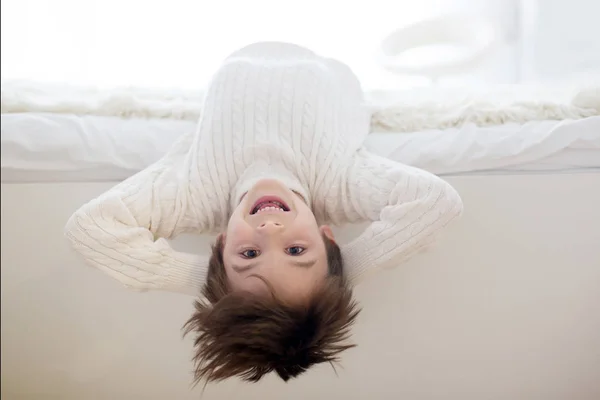 可爱的孩子倒挂的肖像 躺在床上 对着镜头微笑 玩玩具 — 图库照片