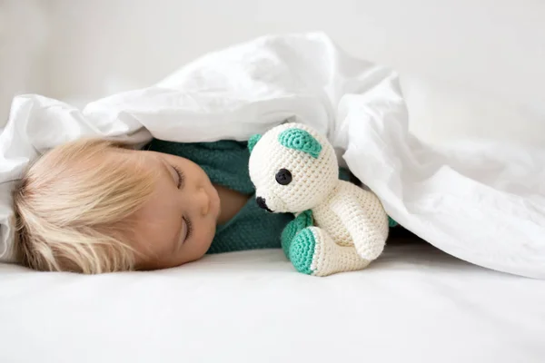 小さなかわいい赤ちゃん男の子 ニットのセーターの子白い日当たりの良い 明るい寝室でカメラで幸せそうに笑ってニット グッズを保持 — ストック写真