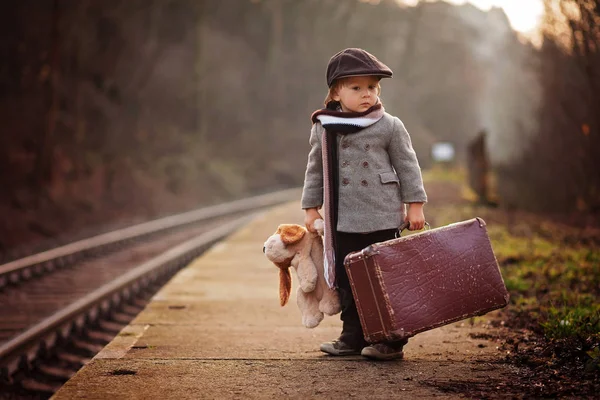 スーツケースやテディベア ビンテージの外観と列車を待っている駅 愛らしい少年 — ストック写真