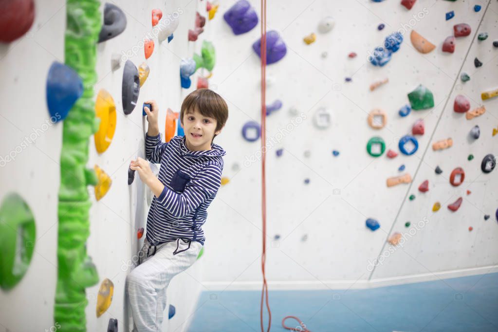 Sweet little preschool boy, climbing wall indoors, having fun, active children