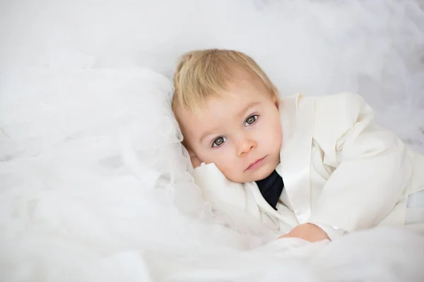 エレガントなハンサムな男の子のタキシード 彼ママ ブライダル ドレス 結婚式に行く準備ができてのベッドに横たわっての肖像画 — ストック写真