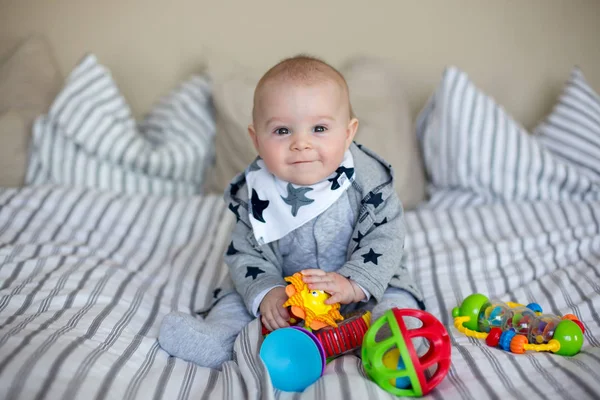赤ちゃんや幼児のカラフルなおもちゃのたくさんのベッドで家庭で遊ぶかわいい小さな男の子 — ストック写真
