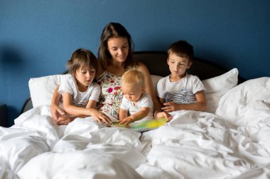 Anne, çocuklarına sabahları evde yatakta bir kitap okuma