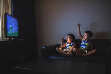 Geceleri evde TV izlerken kanepede oturan çocuk