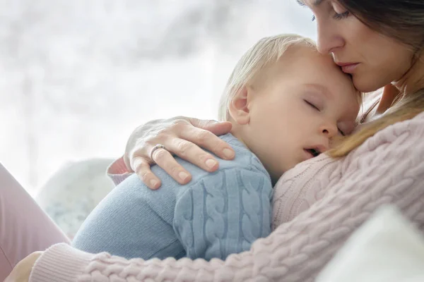 若い母親 抱いて 彼は自宅で 彼女の病気の幼児男の子を保持している日当たりの良いリビング ルーム — ストック写真