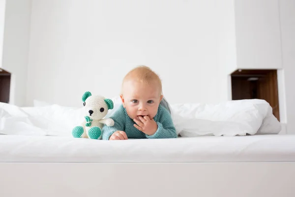 小さなかわいい赤ちゃん男の子 ニットのセーターの子白い日当たりの良い 明るい寝室でカメラで幸せそうに笑ってニット グッズを保持 — ストック写真