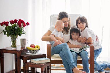 Anne, onun yürümeye başlayan çocuk ve büyük kardeşi, okuma kitabı, gülümseyen, emzirme ile oynama
