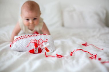 Şirin Bebek yürümeye başlayan çocuk, beyaz ve kırmızı bilezik ile oynuyor. Mart ayında, süsleme sembolü, iplik, Bulgar folklor geleneği, konuksever bahar Martenitsa, beyaz ve kırmızı suşları için iyi sağlık diliyorum