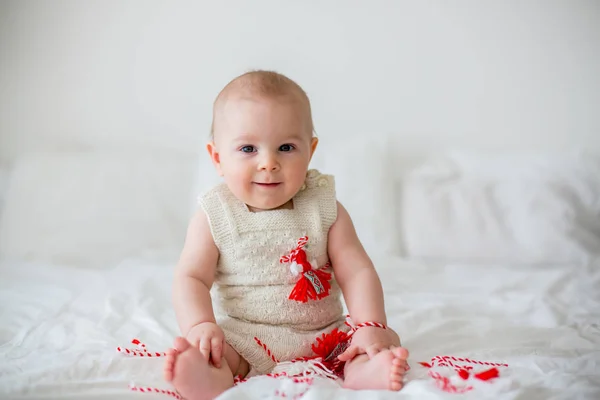 白と赤のブレスレットと遊ぶかわいい赤ちゃん幼児の少年 装飾記号の糸 ブルガリアの民俗伝統 春を迎えて Martenitsa 白と赤系統希望ヒース良い — ストック写真