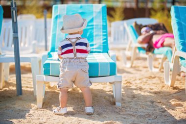 Peluş rahatlatıcı oyuncak ve şapka şemsiye altında sahilde oynarken şık küçük bebeğim