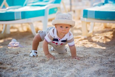 Peluş rahatlatıcı oyuncak ve şapka şemsiye altında sahilde oynarken şık küçük bebeğim