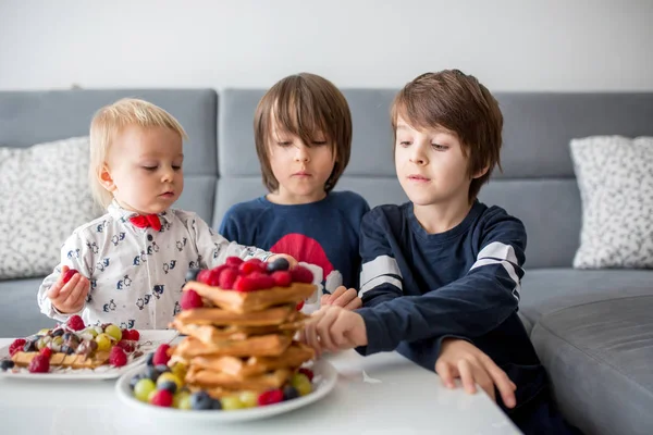 可爱的幼儿生日男孩和他的兄弟们 在家里吃比利时华夫饼 配覆盆子 椰子和巧克力作为早餐 — 图库照片