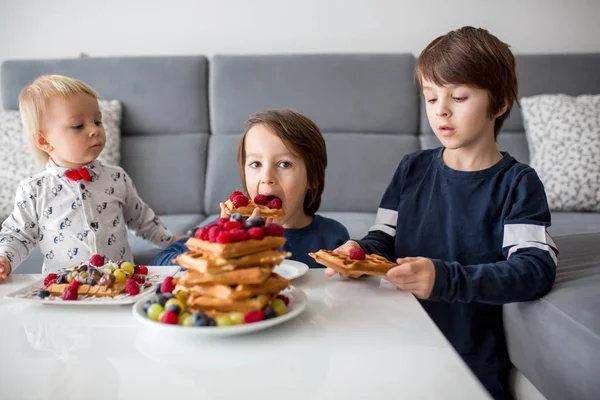可爱的幼儿生日男孩和他的兄弟们 在家里吃比利时华夫饼 配覆盆子 椰子和巧克力作为早餐 — 图库照片