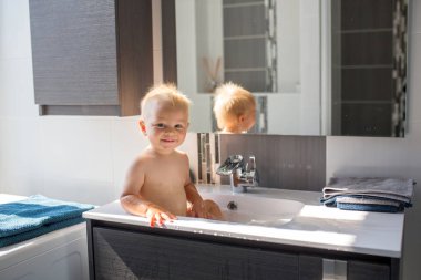 Bebek lavaboda banyo yapıyor. Çocuk köpük ve sabun Bubbl ile oynuyor