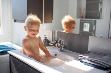 Bebek lavaboda banyo yapıyor. Çocuk köpük ve sabun Bubbl ile oynuyor