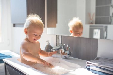 Bebek lavaboda banyo yapıyor. Çocuk köpük ve sabun Bubbl ile oynuyor