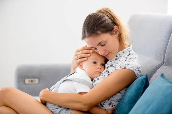 Jonge moeder, zittend thuis in de zonnige woonkamer, knuffelen wit — Stockfoto