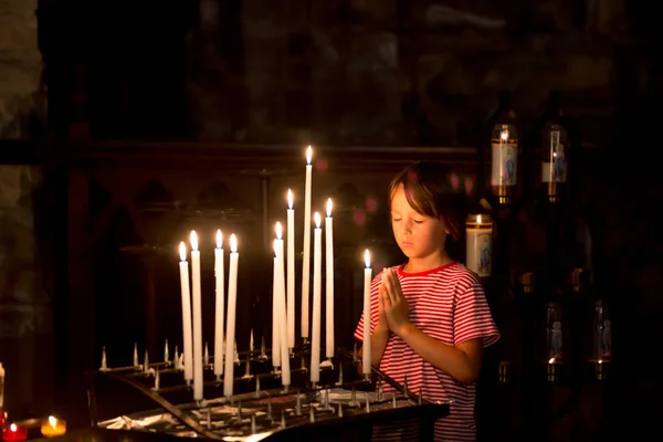 Kleiner Junge betet und stellt eine Kerze in orthodoxe Kirche — Stockfoto