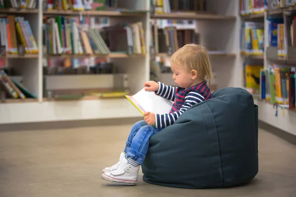 Petit garçon intelligent, s'éduquant dans une bibliothèque, lisant des livres — Photo