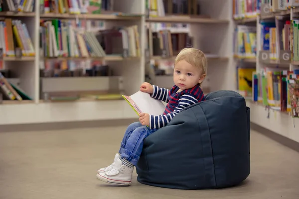 Smart todller boy, educating himself in a library, reading books — Stock Photo, Image