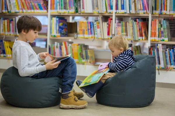 Niños inteligentes, hermanos varones, educándose en una biblioteca — Foto de Stock