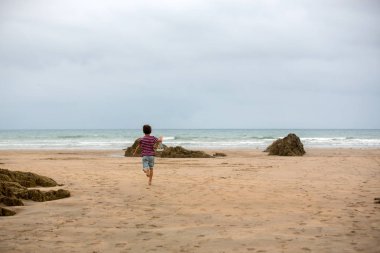 Çocuk plajda kum ile oynar. Oyuncak gemi ile sevimli okul öncesi çocuk