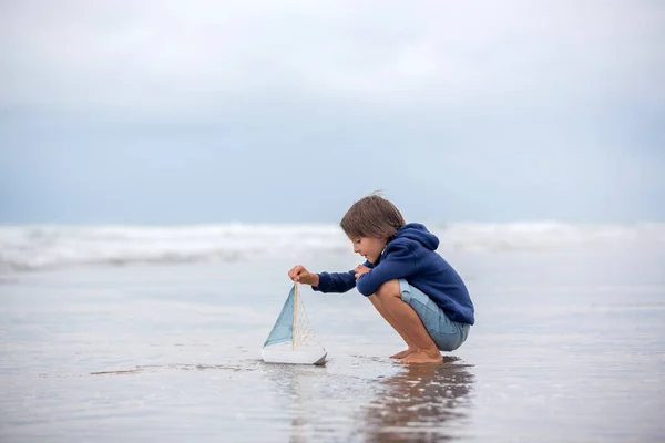 Dziecko gra z piasku na plaży. Cute przedszkola chłopiec z zabawką statek — Zdjęcie stockowe