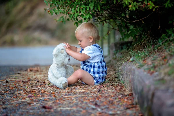 Bedårande småbarn, leka med Nalle Björn i parken — Stockfoto