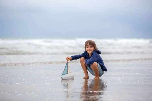 Niño juega con arena en la playa. Lindo niño preescolar con barco de juguete —  Fotos de Stock