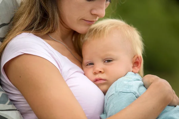 Giovane madre, tenendo il suo bambino carino all'aperto, coccolarlo, kis — Foto Stock