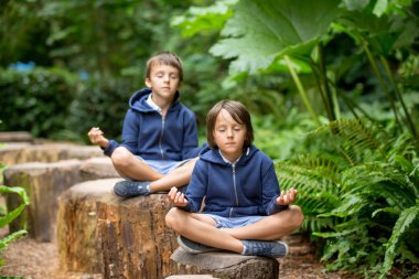 İki okul öncesi çocuk, çocuk borothers, ağaç gövdeleri üzerinde oturan