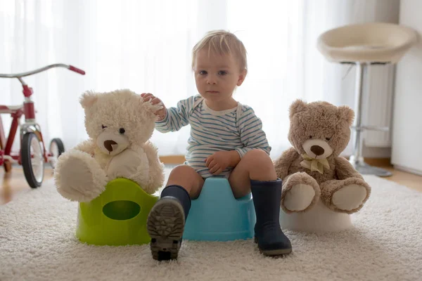 Cute toddler boy, potty training, playing with his teddy bear