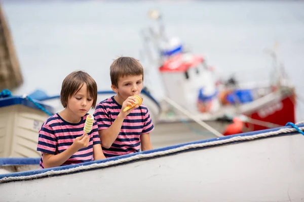 Ragazzi carini, mangiare gelato, seduti in una barca in porto — Foto Stock