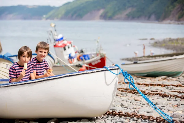 Cute boys, eating ice cream, sitting in a boat in harbor — Stock Photo, Image