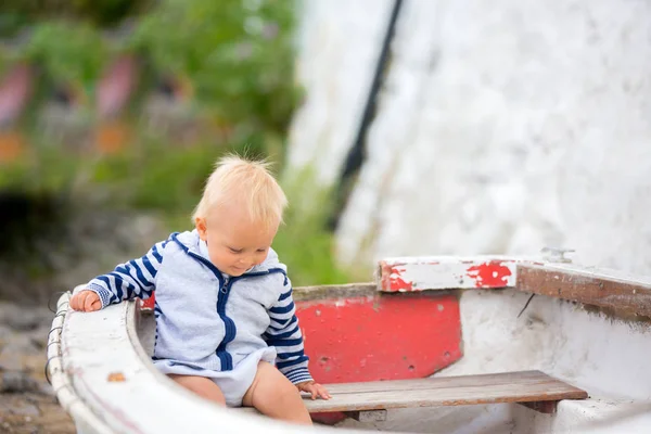 Sweet toddler boy, sitting in a boat in harbor, smiling happily — Stock Photo, Image
