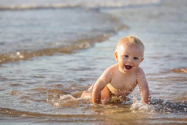 Kisfiú, játék a strandon a vízben, mosolyogva — Stock Fotó