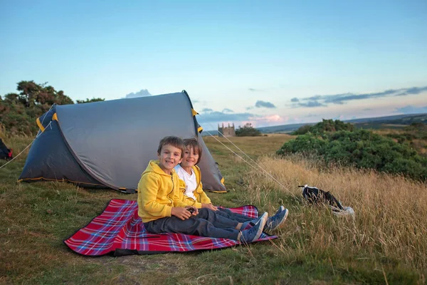 Beautiful family, camping on a hill, enjoying the sunset view on