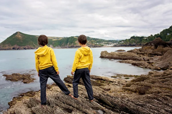 Діти, насолоджуючись тихим похмурим днем на березі океану на глибині — стокове фото