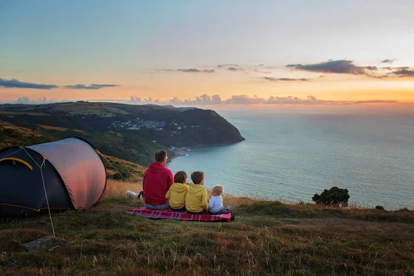 Beautiful family, camping on a hill, enjoying the sunset view on