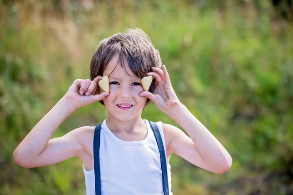 Dulce niño preescolar, niño, sosteniendo galletas delante de sus ojos —  Fotos de Stock