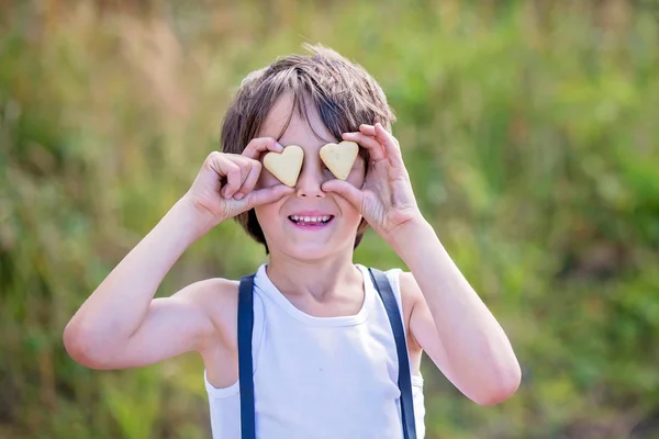 Dolce bambino in età prescolare, ragazzo, tenendo i biscotti davanti ai suoi occhi — Foto Stock