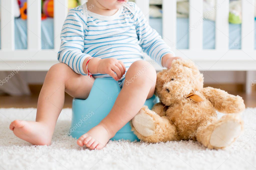 Cute toddler boy, potty training, playing with his teddy bear 
