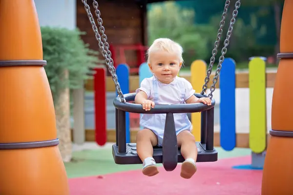 Entzückender kleiner Junge, der mit verschiedenen Fahrgeschäften auf dem Playgdoru spielt — Stockfoto