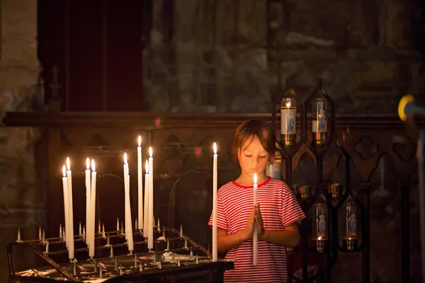 Маленький мальчик молится и ставит свечу в православной церкви — стоковое фото